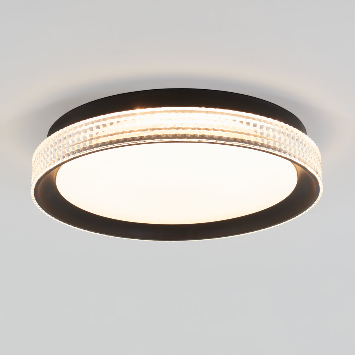 The Artika Aston 15 in. LED modern flush mount light features a black frame, textured clear ring, and white illuminated center, mounted on a plain white ceiling.