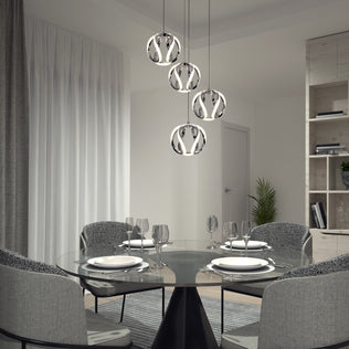 A modern dining room features a round glass table set for four with gray upholstered chairs. Overhead, the Artika Vivaldi LED 4-light pendant adds elegance, while sheer curtains and a plant complete the refined decor.