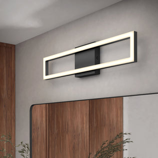 The Artika Dover 27-in Integrated LED 5-CCT Vanity Light Bar with a black base is mounted above a mirror on a light gray wall, bringing contemporary style to this modern bathroom with wood panels and a visible plant in the background.