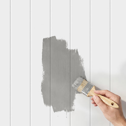 A hand paints gray on Artika AXEN Shilap 48 in. Ready-to-Paint Shiplap MDF Wall Panels (12-Pack).