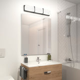 A modern bathroom with a wooden vanity, large mirror, three-light fixture above, toothbrushes in a holder, a towel hanging on the side, and a bathtub with a glass screen and herringbone tile wall.