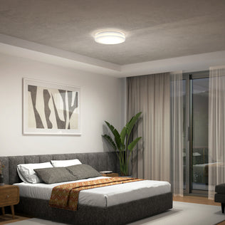 Modern bedroom with a gray bed, abstract art, potted plant, and Artika Hemisphere LED ceiling light near a window with sheer curtains.