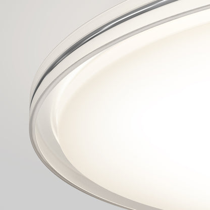 Close-up of the Artika Astrid 16.5 in. LED flush mount light with a frosted glass cover and metallic rim, brightly illuminated against a light grey background; features 5 CCT settings and comes with a remote.