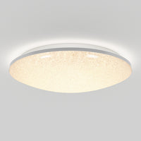 The Artika Sparkle LED flush mount light features a round, textured surface and emits a warm, even glow. Mounted on a white ceiling, this modern fixture comes with a remote for easy control.