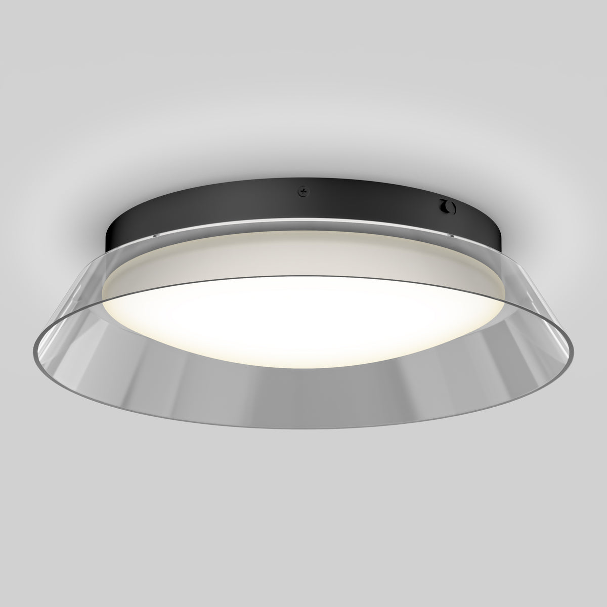 A modern ceiling light fixture with a black circular base, a frosted white diffuser, and a clear angled outer rim, emitting a soft, even glow against a light gray background.