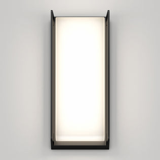 The Artika Ryker smart RGB indoor-outdoor wall light features a black frame and softly glowing white center, mounted on a plain light gray wall.