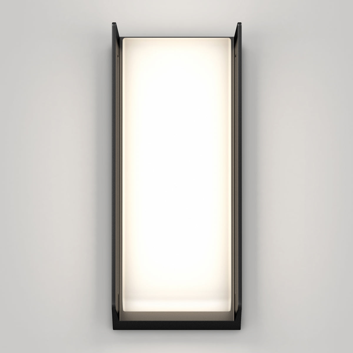 A modern rectangular wall sconce with a black frame and frosted glass, emitting a soft white light, mounted on a plain light gray wall.