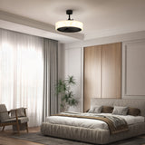 A modern bedroom with a large bed, neutral bedding, wood accent wall, floor plant, armchair, and sheer curtains. A contemporary ceiling light fixture hangs above the bed. Natural light fills the room.