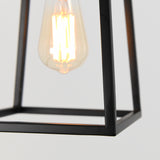 A close-up of a glowing vintage-style light bulb inside a minimalist black metal frame against a plain light background.