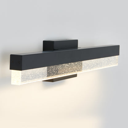 The Artika Bubble Bar LED bathroom vanity light features a modern rectangular design with a matte black finish and bubble-textured clear glass, casting soft, even light on any white wall.