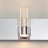 A modern wall sconce with a cylindrical glass cover, chrome base, and small LED lights inside, mounted on a mirrored surface.