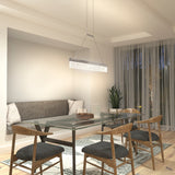 Modern dining room with a glass table, four wooden chairs with gray cushions, a gray cushioned bench, a contemporary rectangular pendant light, a plant in the corner, and sheer curtains covering large windows.