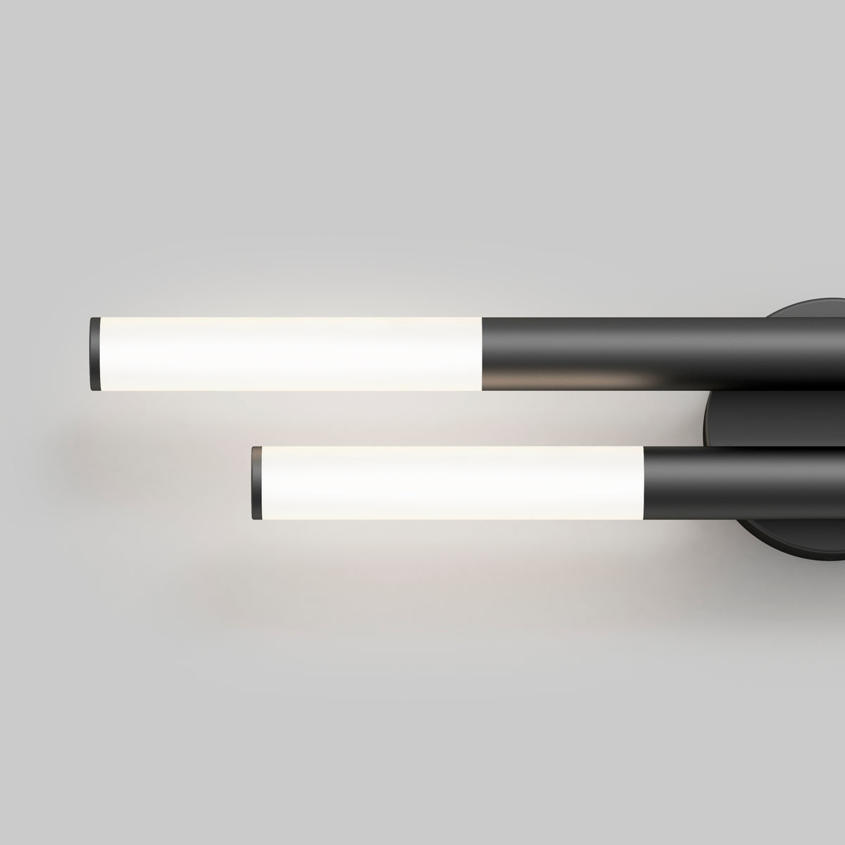 Minimalist wall-mounted light fixture with two cylindrical, horizontal white LED tubes attached to a round black base on a plain gray background.