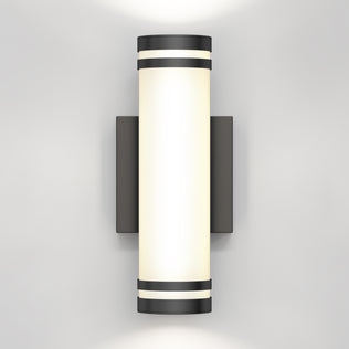 The Artika Bradley modern LED indoor-outdoor wall light 3 CCT features a cylindrical frosted glass shade and black metal accents on a rectangular base, casting soft up and down lighting against your wall.