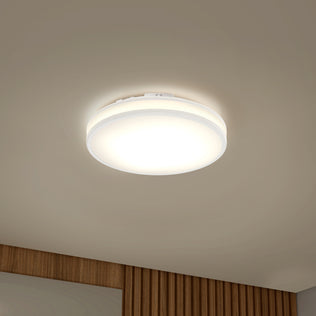 The Artika Hemisphere 15″ LED ceiling light with 5 CCT brightens a beige ceiling above a wooden paneled wall.