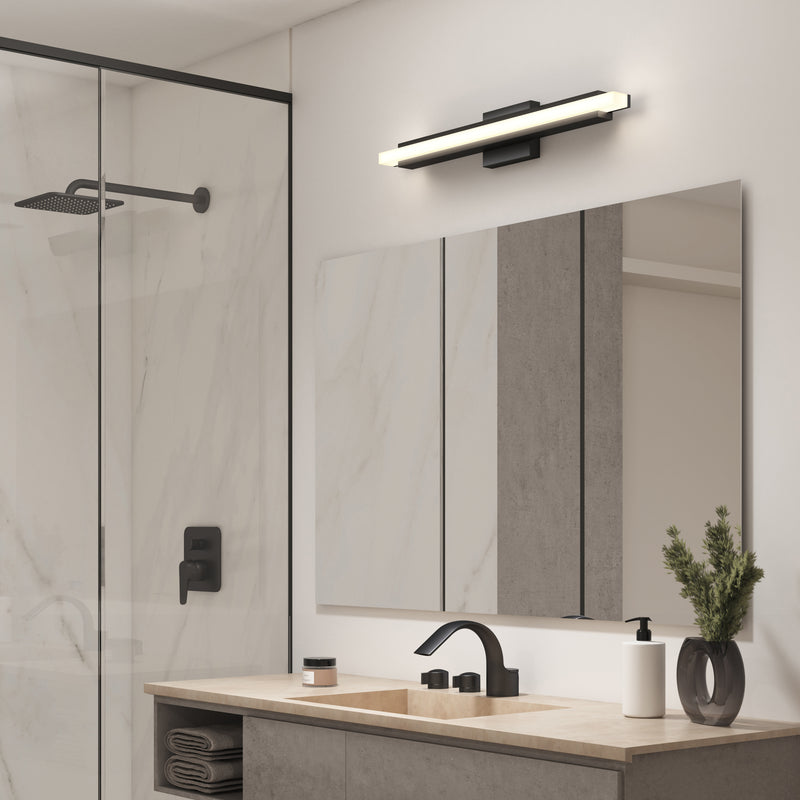 Modern bathroom with a glass shower, black fixtures, a vanity plant, and the Artika Ophelia LED vanity light above the large mirror.
