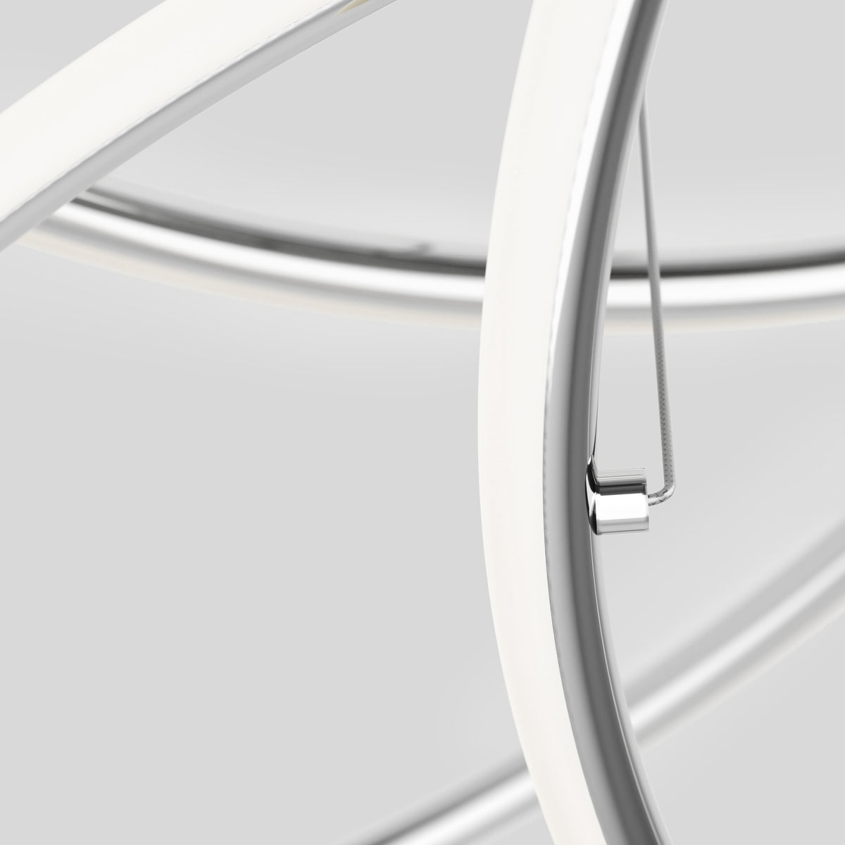 Close-up of intersecting white and chrome metal tubes with smooth curves against a light gray background, showing a sleek, modern design.