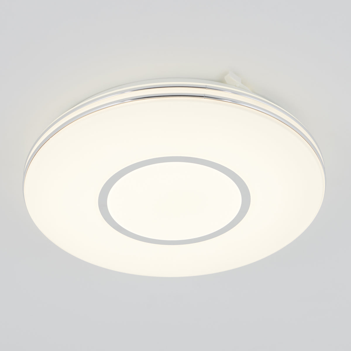The Artika Horizon 13 in. LED flush mount light features a dimmable glowing white center and silver ring, mounting elegantly on ceilings.