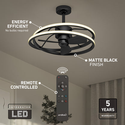 The Artika Coda 23 in. LED modern ceiling fan features a matte black finish, circular LED light kit, and remote control. This energy-efficient fan is LED-integrated and comes with a 5-year warranty. A curtain and plant can be seen in the background.