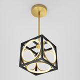 A modern pendant light with a gold ceiling mount and rod, featuring a black cubic frame enclosing glowing gold circular rings, suspended against a plain white background.