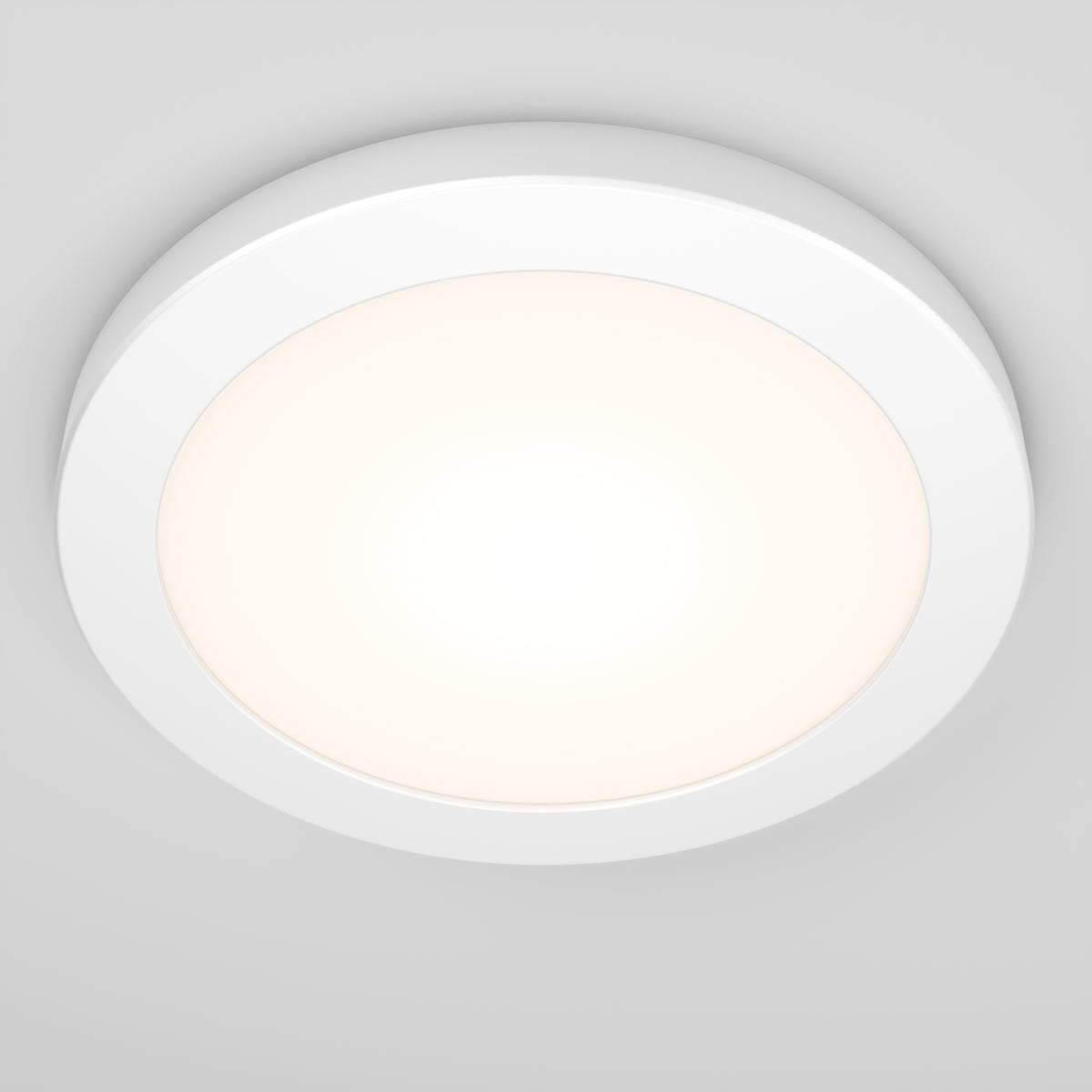 A modern, round LED ceiling light with a white frame, mounted on a white ceiling. The light is turned on, emitting a soft, even glow.