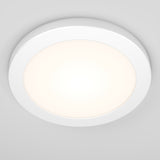 A modern, round LED ceiling light with a white frame, mounted on a white ceiling. The light is turned on, emitting a soft, even glow.