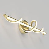 A modern gold wall sconce with a central light bar and decorative, looping curved elements, mounted on a round base against a light gray wall.