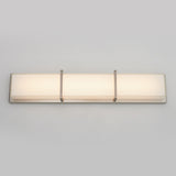 A modern rectangular wall sconce with a frosted white glass shade and three metal brackets, mounted on a light gray wall.