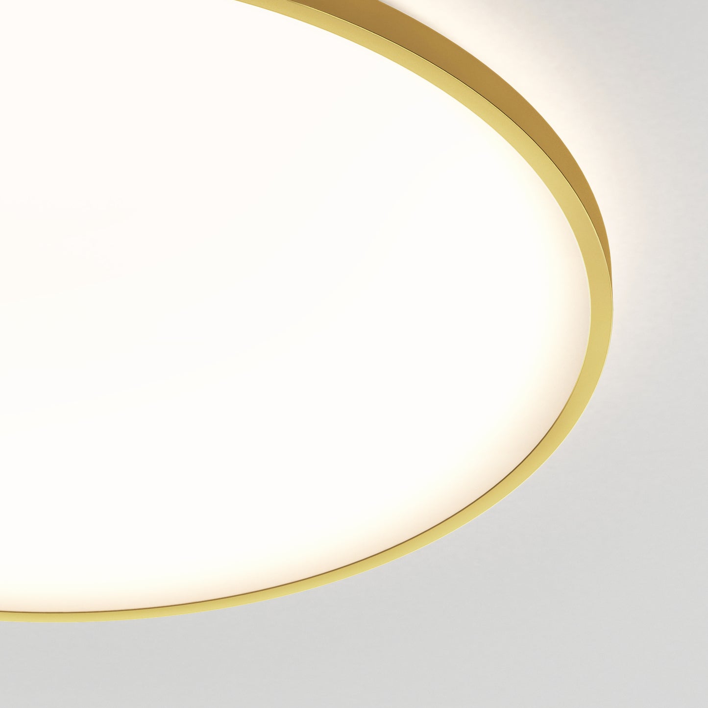 A close-up of the Artika Europa 21 in. LED modern flush mount light with remote, featuring a gold rim and glowing brightly against a white ceiling. Only part of the fixture appears in the upper left corner.