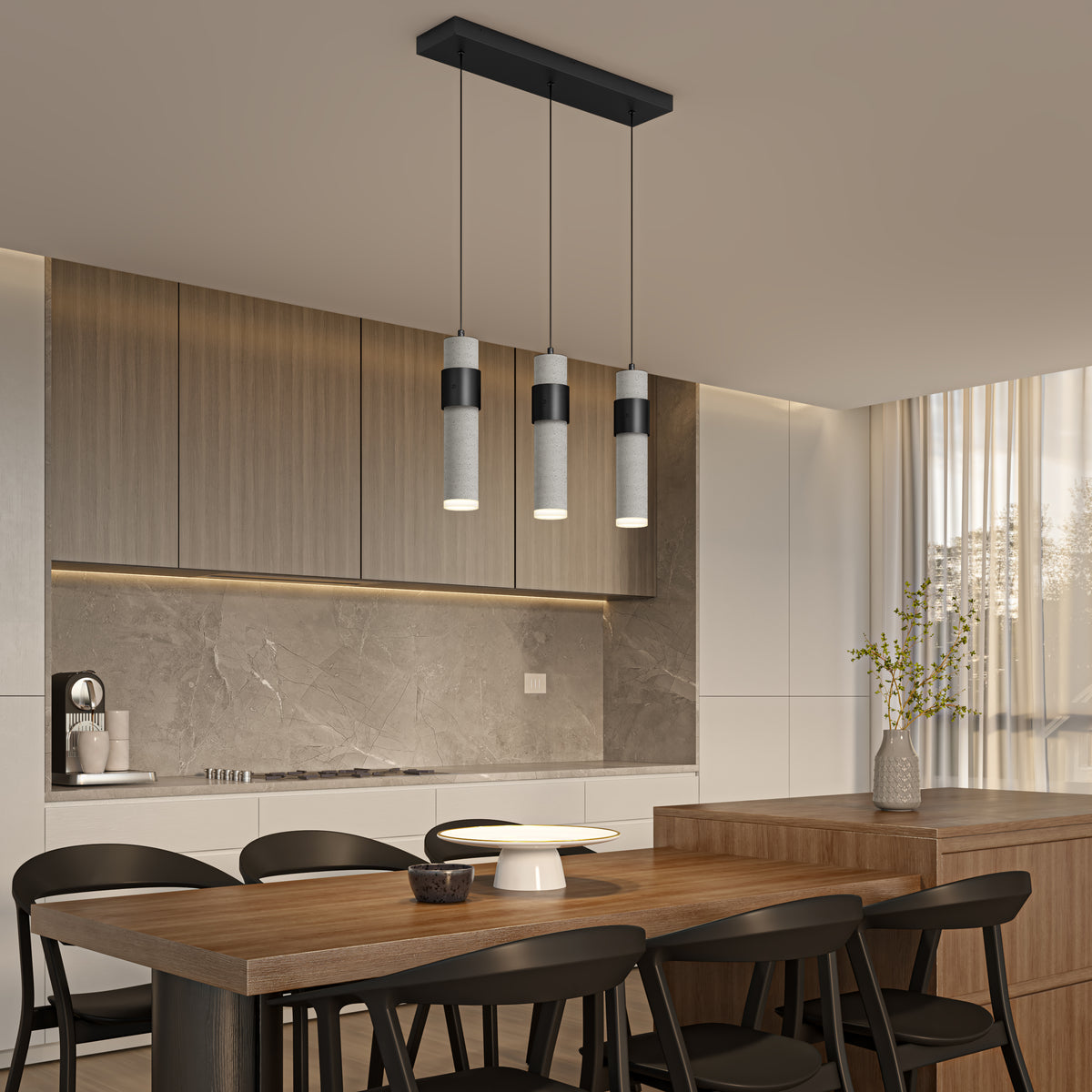 Modern kitchen with wooden dining table, black chairs, and three hanging pendant lights. Cabinets and backsplash are light wood and gray stone. Sunlight streams through sheer curtains by a vase with branches on the island.