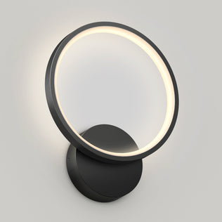 The Artika Solis modern LED indoor-outdoor wall light 5 CCT features a circular LED ring and black base, casting a soft, even glow against a plain light-colored wall.