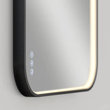 A close-up of a modern rectangular smart mirror with rounded corners, illuminated by built-in LED lights along the edge and touch-sensitive control icons on the lower left corner.