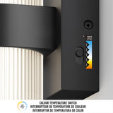 Close-up of a color temperature switch on a modern black lamp, showing a small slider with color temperature options from cool white to warm yellow. Text below reads Colour Temperature Switch in three languages.