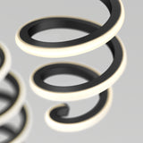 A close-up of two black metallic spiral coils with glowing white edges, set against a soft gray background. The focus is on the curves and illumination of the spirals.