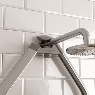 Close-up of the Artika O2 Hanging Shower Caddy, mounted on a white subway tile bathroom wall. The Artika brand name is visible on the metal bracket.