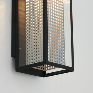 Close-up of the Artika Meteor LED indoor-outdoor wall light, featuring a black metal frame and perforated panel. Mounted on a light wall, it casts patterned illumination through its tiny holes.