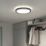 A modern round ceiling light fixture illuminates a minimalist closet with gray cabinets, hanging clothes, and storage boxes on an upper shelf. The space is bright and neatly organized.