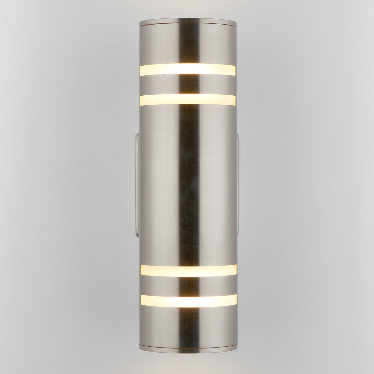 The Artika Voltz indoor-outdoor wall light is a modern cylindrical sconce in brushed metal, featuring horizontal frosted light strips glowing at the top and bottom, mounted vertically against a light gray background.
