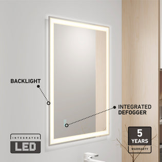 The Artika Sofia LED mirror 3 CCT with defogger is mounted on a light gray wall, featuring an LED backlight and icons for its 5-year warranty. A faucet and part of a wooden cabinet are also visible nearby.