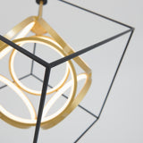 A modern pendant light featuring a black geometric cube frame with glowing circular LED elements and gold accents, suspended against a plain, light background.