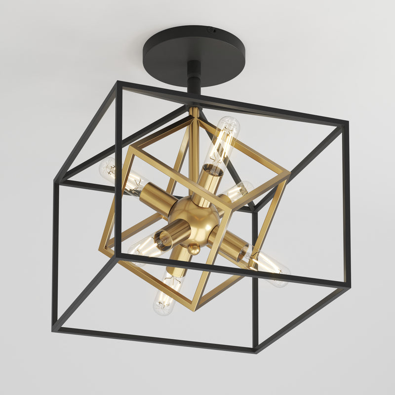 The Artika Imperium flush mount light features a modern geometric design with a black metal outer cube, an inner gold cube holding exposed bulbs, and a black base.