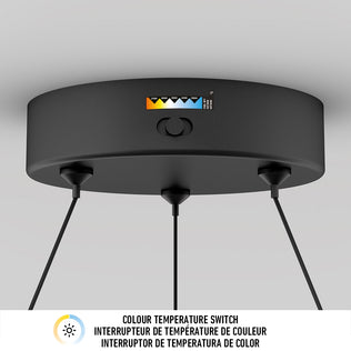 The Artika Bjorn modern LED pendant light 5 CCT is a round black ceiling fixture with three hanging cords and a top color temperature switch, offering customizable warm to cool settings. Below, COLOUR TEMPERATURE SWITCH appears in three languages.