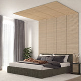 Modern bedroom with a gray bed, textured bedding, and pillows. Wooden slats decorate the wall and ceiling above the bed. Large windows with sheer and gray curtains, a plant, and a soft white rug complete the room.