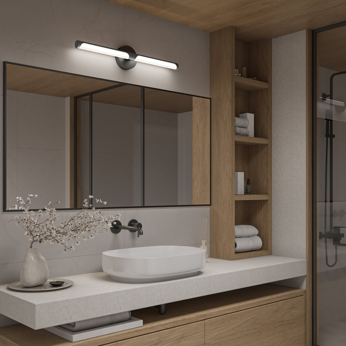 Modern bathroom with a large mirror, white countertop, vessel sink, black faucet, wall-mounted light, open wooden shelves with towels, and glass shower enclosure. Vase with branches decorates the counter.