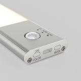 A close-up of a slim, silver LED light with a motion sensor, indicator icons, and three buttons labeled “DIM,” “COLOR,” and “MODE” on one end, set against a light gray background.