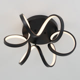 A modern ceiling light fixture with black, ribbon-like LED strips forming looping, abstract shapes, mounted on a round black base against a plain white ceiling.