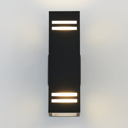 The Strike indoor-outdoor wall light by Artika features a modern black design with horizontal rectangular cutouts, casting soft white light both upward and downward when mounted on a light-colored wall.