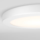 A close-up of a modern, circular white ceiling light fixture, softly illuminated against a plain white ceiling.