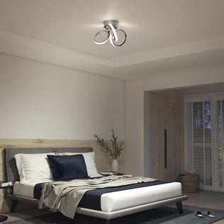 Modern bedroom with a neatly made bed, accent pillows, and the Artika Swirl LED flush mount (1300 lumens) on the ceiling.
