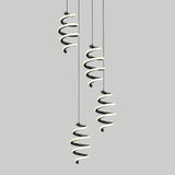 Three modern pendant lights with spiral, ribbon-like designs hang from the ceiling against a plain, light gray background. The lights emit a soft glow along the curves of the spirals.